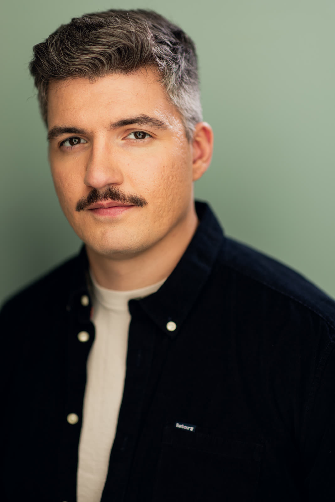 Eugene Romanchuk, headshot: navy shirt against a sage green background