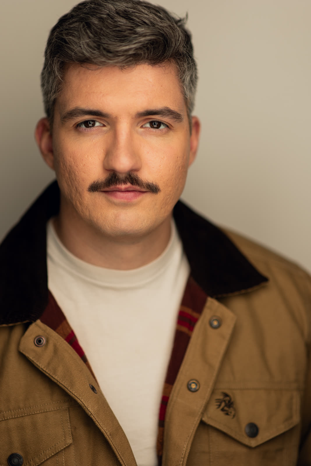 Eugene Romanchuk, theatrical headshot: tan work jacket against a cream background